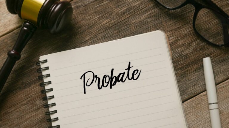 Judge's gavel, glasses, pen and notebook with word Probate