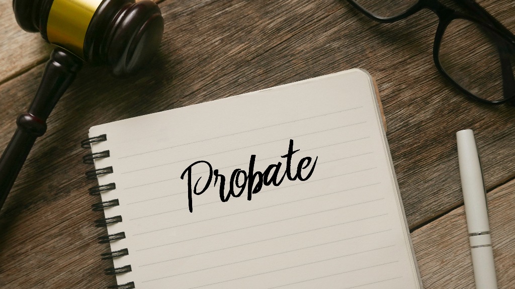 Judge's gavel, glasses, pen and notebook with word Probate