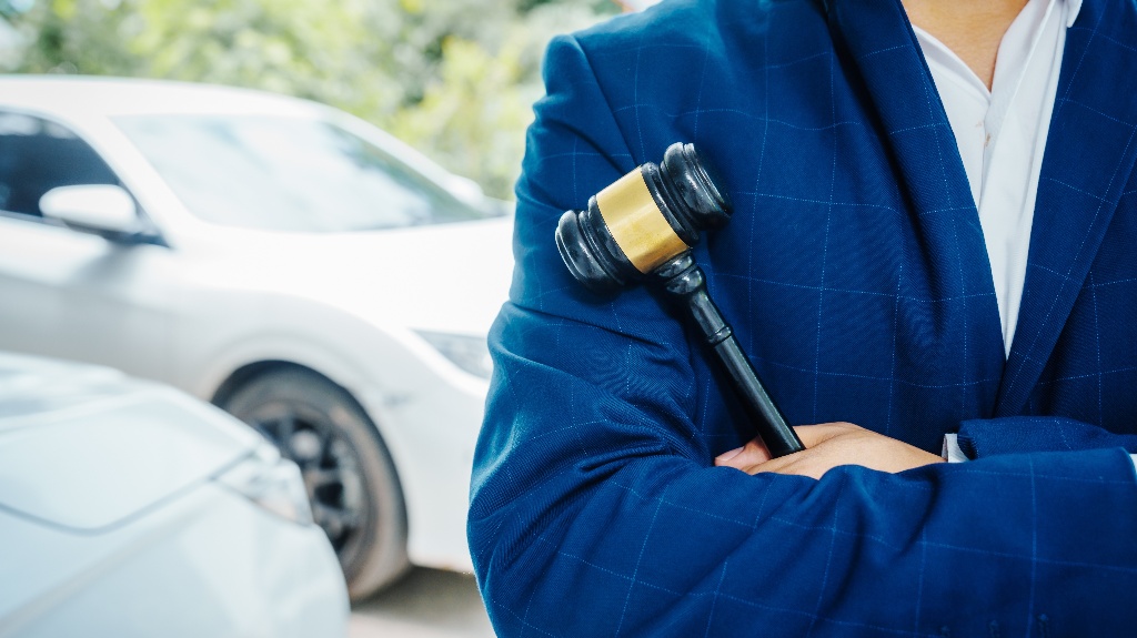 lawyer is holding judge's gavel and standing in front of a car